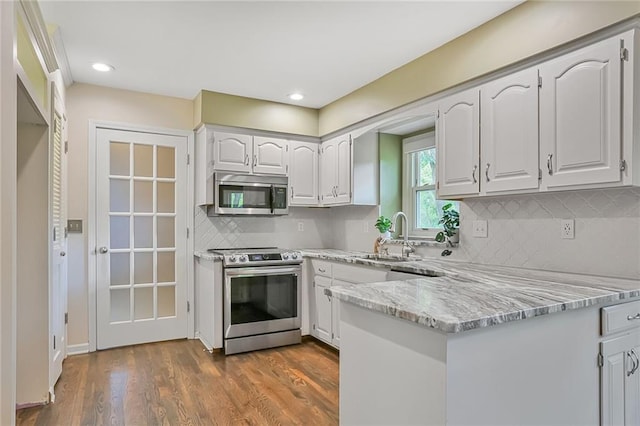 15819 W 147th Ter, Olathe, KS 66062 - kitchen with appliances with stainless steel finishes, a sink, a peninsula, backsplash, and dark wood-type flooring