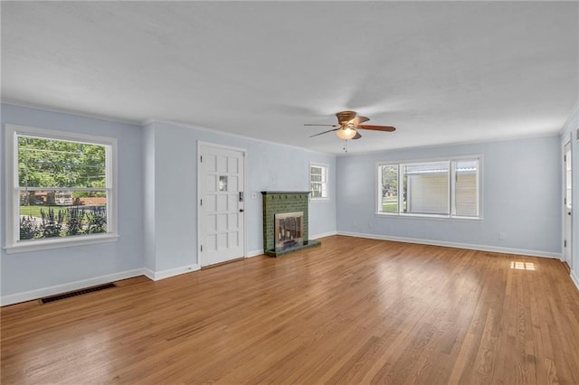 unfurnished living room featuring light wood-style floors, a wealth of natural light, a brick fireplace, and visible vents