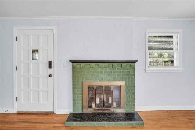 living area with ornamental molding, a fireplace, and wood finished floors