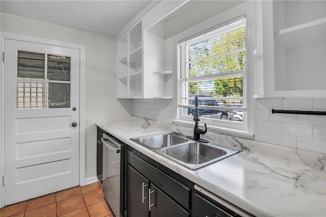 kitchen featuring open shelves, a sink, a textured ceiling, tasteful backsplash, and stainless steel dishwasher