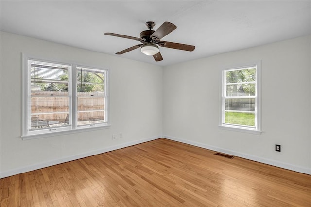 unfurnished room featuring baseboards, visible vents, a wealth of natural light, and light wood-style flooring