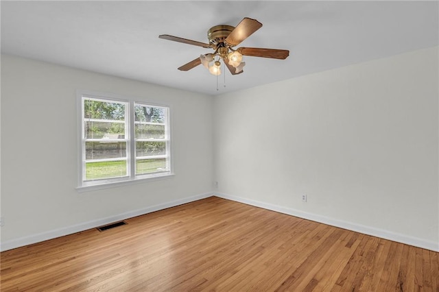 spare room with baseboards, a ceiling fan, light wood-style flooring, and visible vents