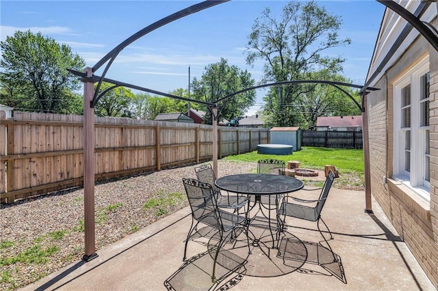 view of patio with outdoor dining area, a fenced backyard, and a fire pit