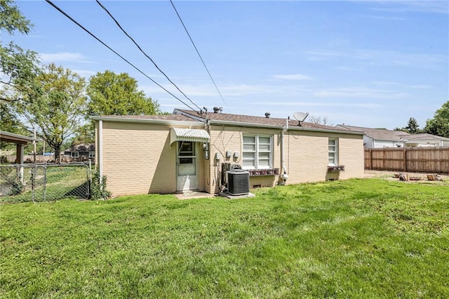 back of house featuring a yard, brick siding, central AC, and fence