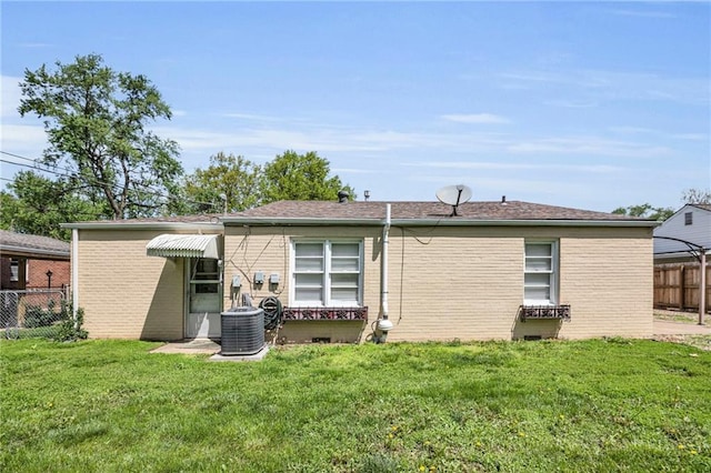 rear view of property with a lawn, brick siding, central AC, and fence