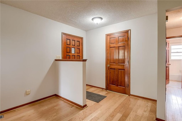 entrance foyer with baseboards, a textured ceiling, and light wood finished floors
