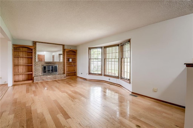 unfurnished living room with visible vents, a textured ceiling, baseboards, and light wood-style floors