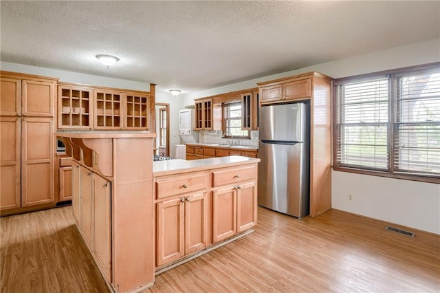 kitchen with freestanding refrigerator, visible vents, light wood-style flooring, and a center island
