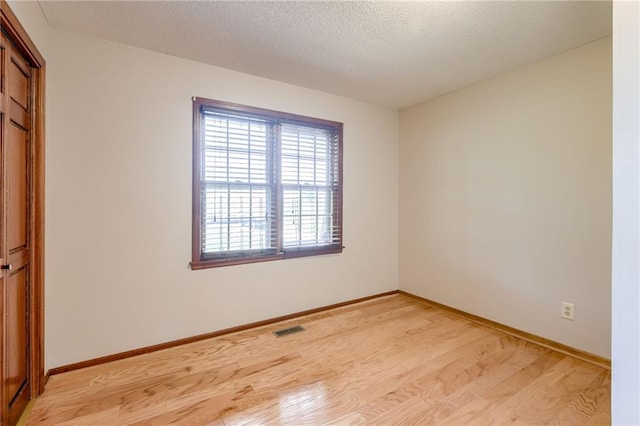 unfurnished room with baseboards, plenty of natural light, light wood-type flooring, and visible vents