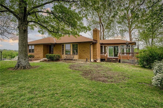 back of property featuring a lawn, brick siding, a chimney, and a wooden deck