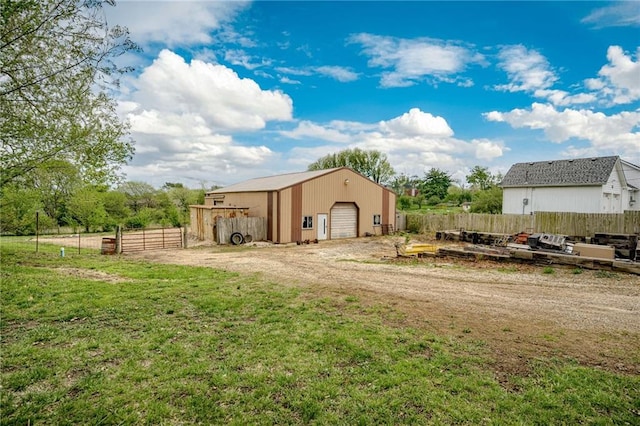view of yard with a detached garage, fence, and an outbuilding