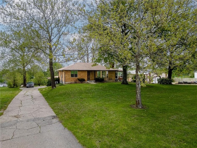 ranch-style home featuring covered porch, brick siding, a front yard, and aphalt driveway