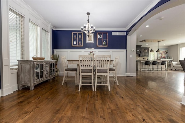 13017 Kelli Dr, Kearney, MO 64060 - dining area with a decorative wall, crown molding, a chandelier, dark wood-style floors, and arched walkways