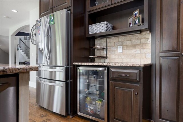 13017 Kelli Dr, Kearney, MO 64060 - indoor dry bar with stainless steel refrigerator with ice dispenser, wine cooler, tasteful backsplash, stairway, and wood finished floors