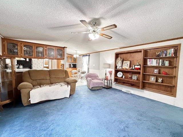 carpeted living area with visible vents, ornamental molding, ceiling fan, and a textured ceiling