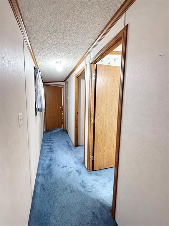 corridor with ornamental molding, a textured ceiling, and carpet