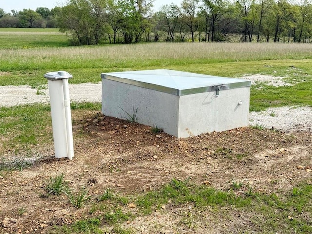 entry to storm shelter featuring a rural view