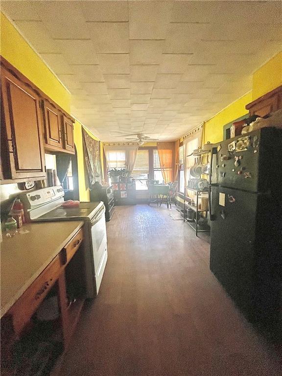 602 E 4th St, Cherryvale, KS 67335 - kitchen with washer / dryer, brown cabinets, dark wood-type flooring, and freestanding refrigerator