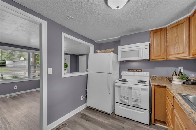 5315 Hardy Ave, Raytown, MO 64133 - kitchen with light wood finished floors, white appliances, a textured ceiling, and visible vents