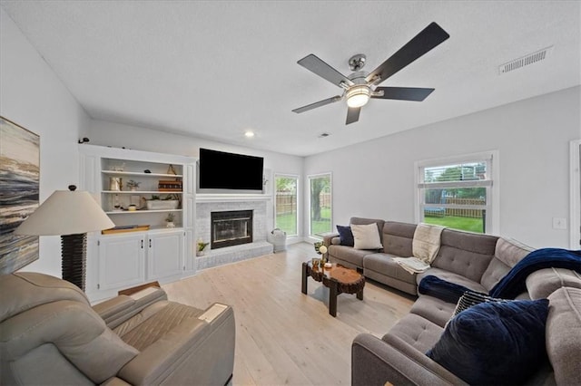living area with a healthy amount of sunlight, ceiling fan, light wood-style flooring, and visible vents