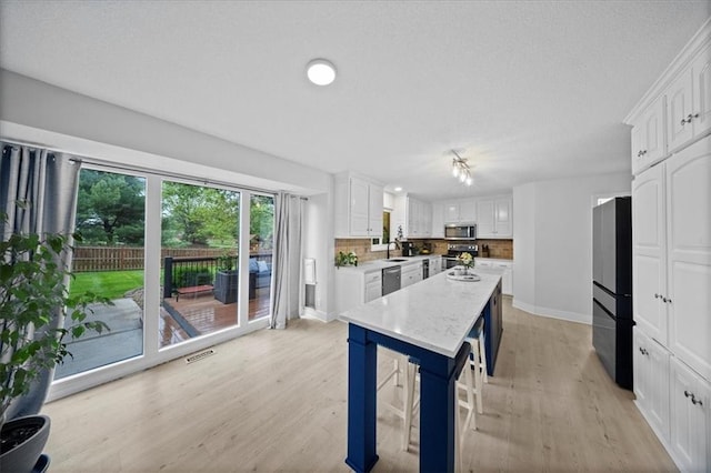 kitchen featuring visible vents, appliances with stainless steel finishes, light wood-style flooring, baseboards, and white cabinetry