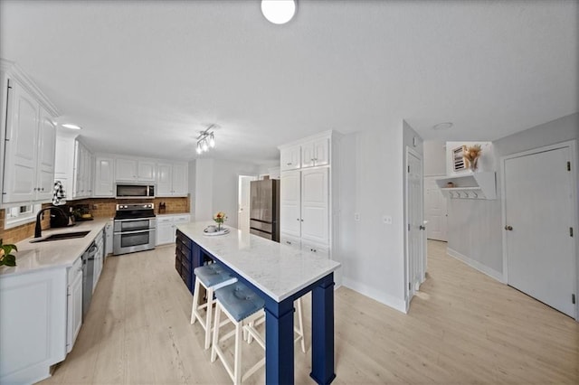 kitchen featuring light wood-style floors, white cabinets, stainless steel appliances, and tasteful backsplash