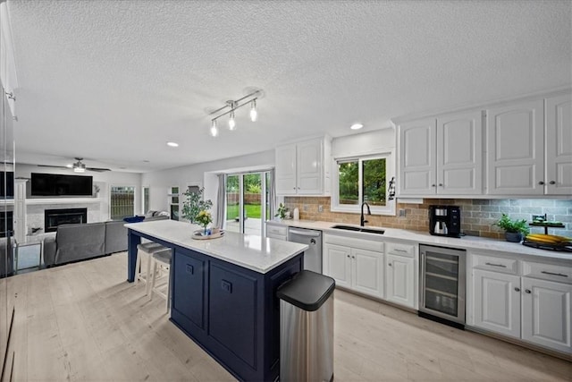 kitchen featuring a sink, dishwasher, a ceiling fan, white cabinetry, and wine cooler