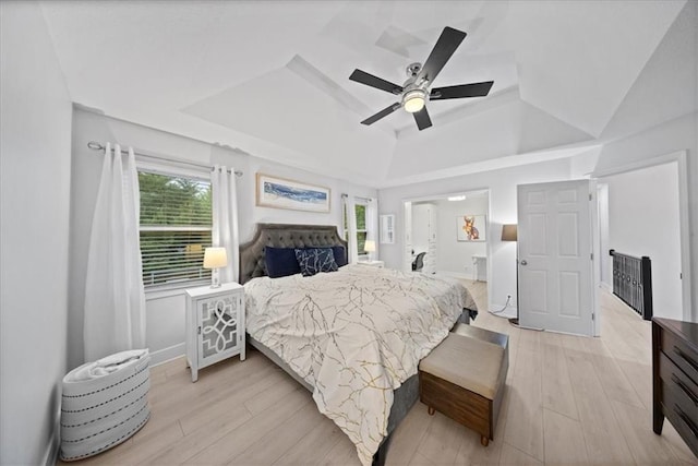 bedroom with light wood-style floors, a raised ceiling, ceiling fan, and vaulted ceiling