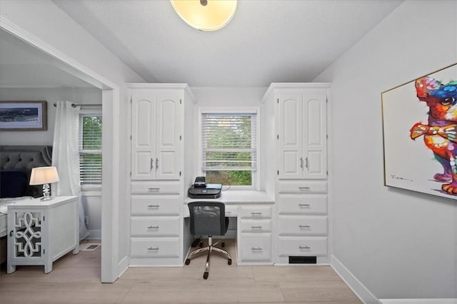 office area featuring baseboards, a wealth of natural light, built in study area, and light wood-type flooring