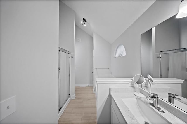 full bathroom with vanity, lofted ceiling, wood finished floors, baseboards, and a stall shower