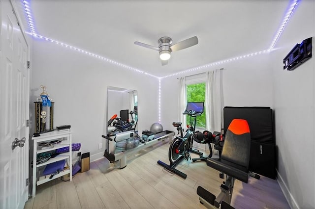 exercise room with baseboards, ceiling fan, and wood finished floors