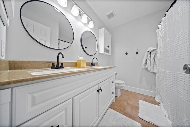 bathroom with a sink, toilet, double vanity, and visible vents