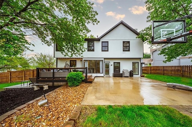 rear view of house featuring a fenced backyard, a wooden deck, and a patio area
