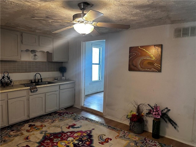 300 W Sea Ave, Independence, MO 64050 - kitchen with a sink, light wood-style flooring, light countertops, baseboards, and a ceiling fan