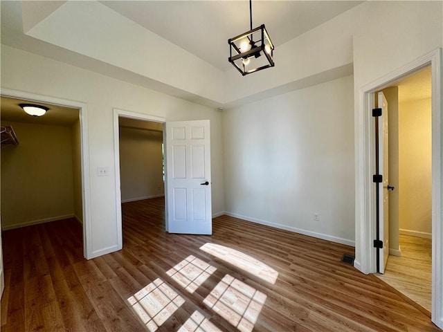 1502 6th Ave, Saint Joseph, MO 64505 - unfurnished bedroom featuring baseboards, a chandelier, wood finished floors, and visible vents