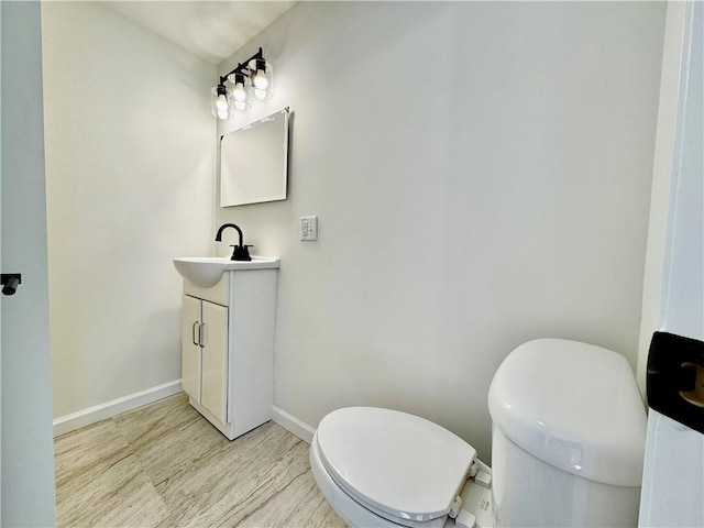 1502 6th Ave, Saint Joseph, MO 64505 - half bath with baseboards, vanity, toilet, and wood finished floors