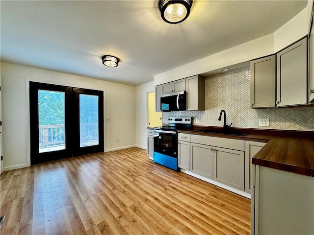 1502 6th Ave, Saint Joseph, MO 64505 - kitchen featuring a sink, wooden counters, stainless steel appliances, decorative backsplash, and light wood-type flooring