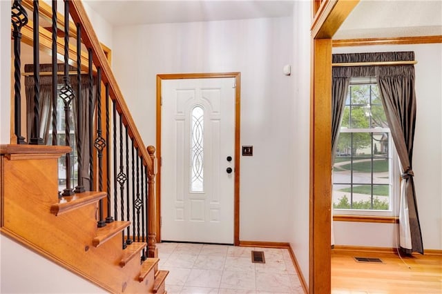 foyer entrance featuring visible vents, baseboards, and stairway