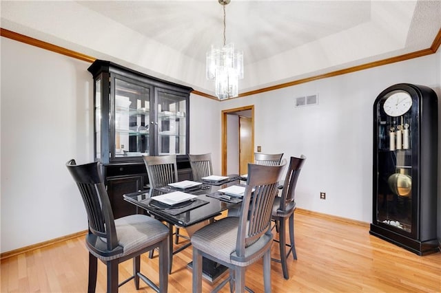 dining room with a notable chandelier, light wood-style floors, baseboards, visible vents, and ornamental molding