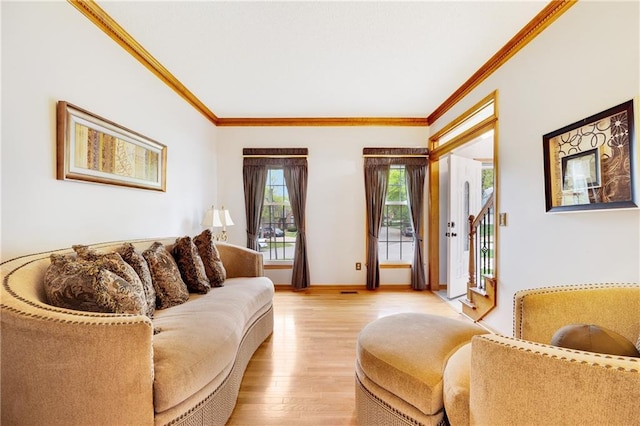 living room featuring crown molding, baseboards, and light wood finished floors