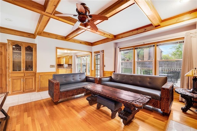 living room featuring a ceiling fan, wainscoting, beam ceiling, light wood finished floors, and coffered ceiling