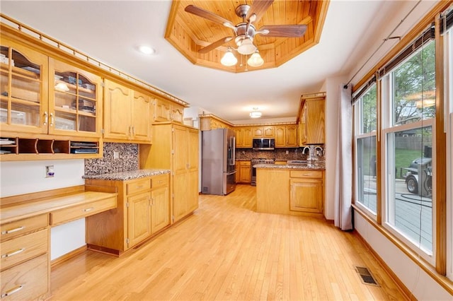 kitchen with a tray ceiling, visible vents, a sink, light wood finished floors, and stainless steel appliances