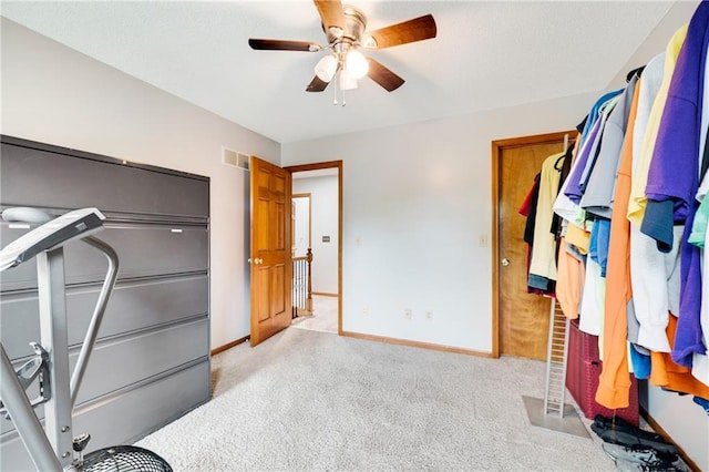 interior space featuring visible vents, baseboards, ceiling fan, and light carpet