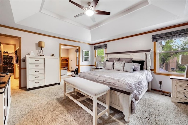 bedroom with a raised ceiling, baseboards, light carpet, and a ceiling fan