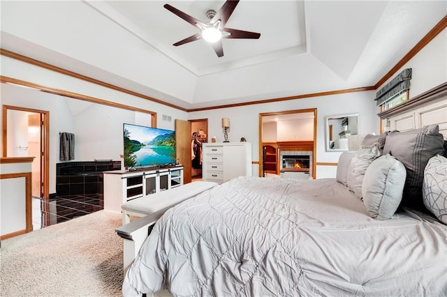 bedroom featuring ceiling fan, a glass covered fireplace, a spacious closet, and a raised ceiling