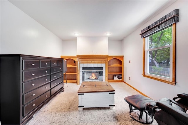 carpeted living room featuring baseboards and a tiled fireplace