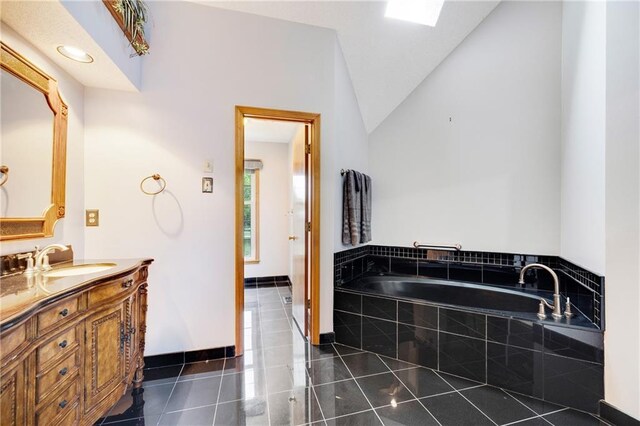 bathroom with a garden tub, vaulted ceiling, vanity, tile patterned floors, and baseboards