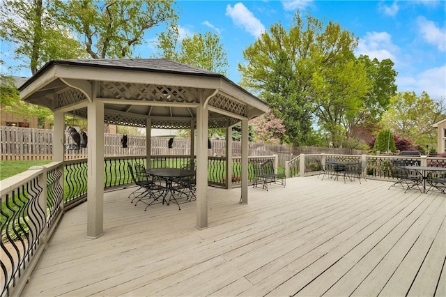 wooden terrace featuring a gazebo, outdoor dining area, and a fenced backyard