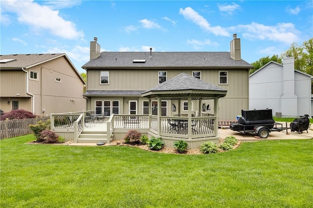 rear view of house with a lawn, a deck, a gazebo, and a chimney