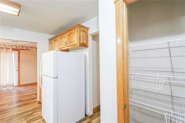 kitchen with baseboards, freestanding refrigerator, and light wood-style floors